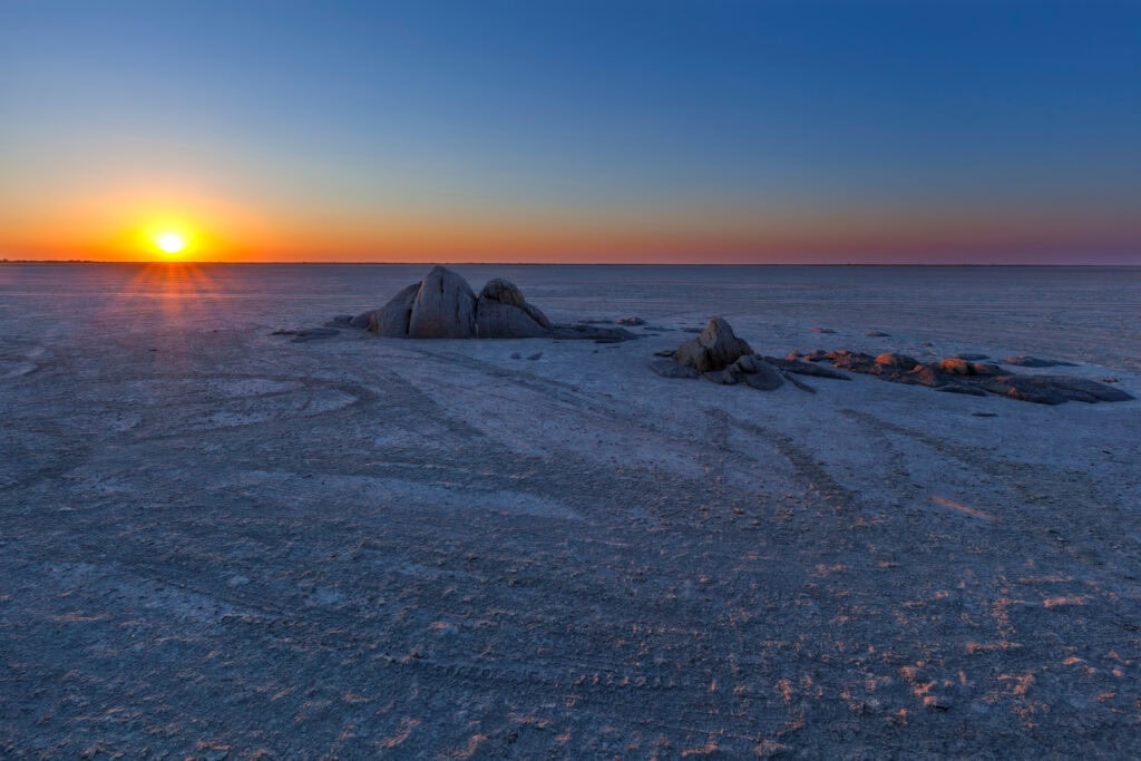 Sunset over the Makgadikgadi Pans, showcasing the vast, arid beauty of Botswana's desert landscape during a Desert and Delta Safari.